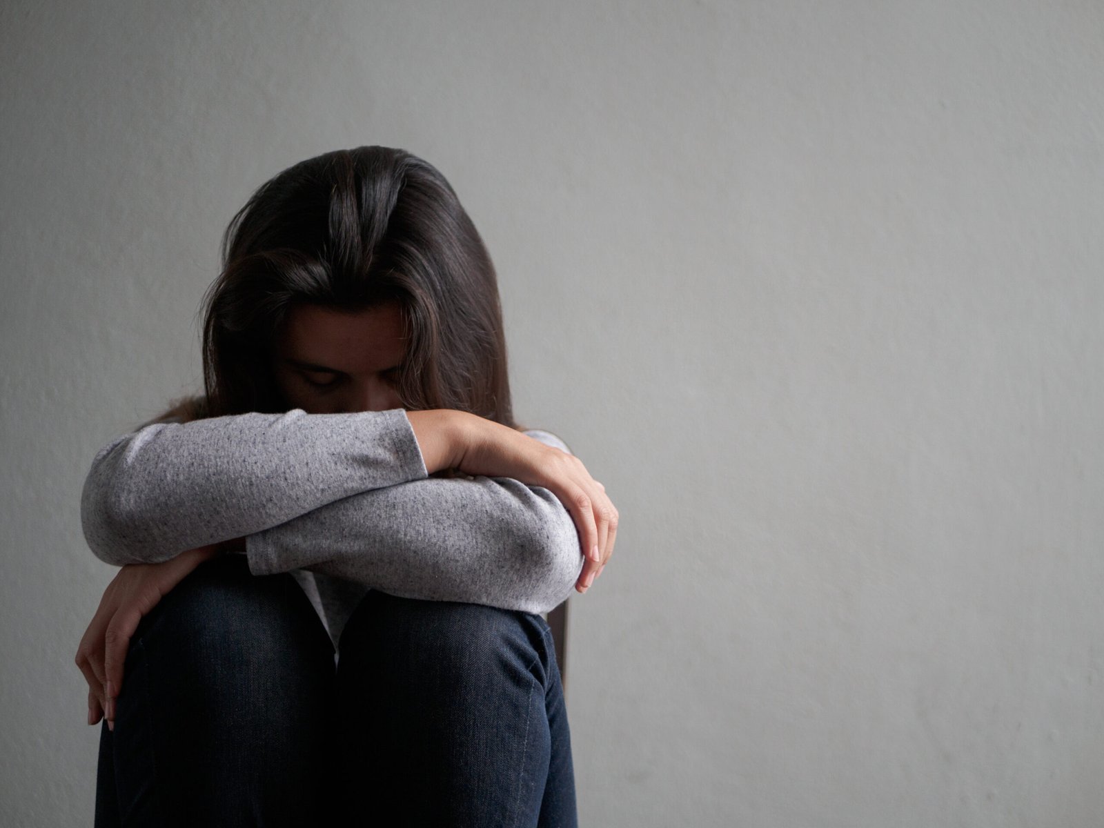 Depressed woman sitting on a chair in dark room at home. Lonly , sad, emotion concept.